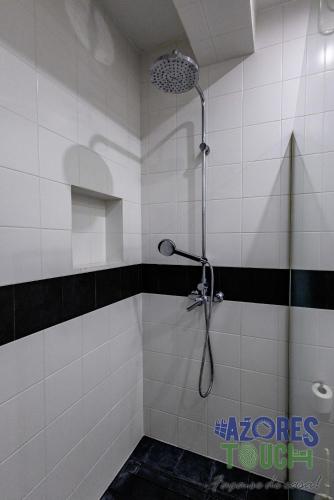 a shower in a bathroom with black and white tiles at Casa da Misericordia in Praia da Vitória