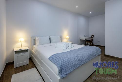 a bedroom with a large white bed with a blue blanket at Casa da Misericordia in Praia da Vitória