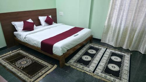 a bedroom with a bed with two rugs on the floor at Tree Top Residency in Mysore