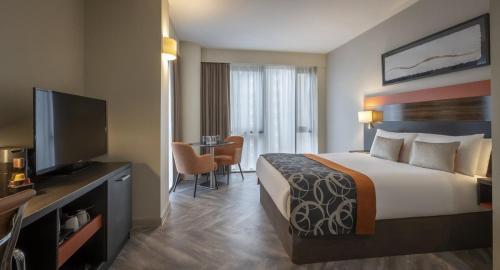 a hotel room with a bed and a flat screen tv at Clayton Hotel Cardiff in Cardiff