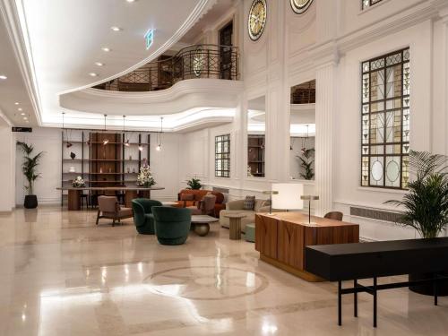 a lobby with couches and tables in a building at Mövenpick Hotel Budapest Centre in Budapest