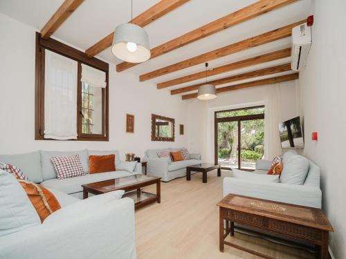 a living room with white furniture and wooden ceilings at Casa Rural El Charruado in Sanlúcar de Barrameda