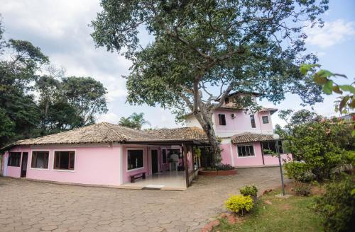 a pink house with a tree in front of it at Chalés Casa Rosa in Alto Paraíso de Goiás