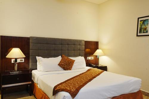 a hotel room with a large bed and two lamps at Central boutique hotel in Morādābād
