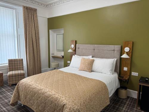 a bedroom with a large bed and a chair at Sandvilla Guesthouse in Oban
