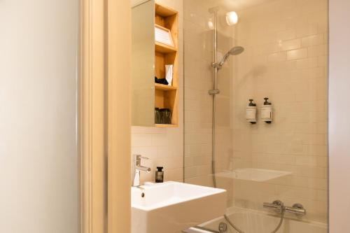 a white bathroom with a sink and a shower at 9Hotel Central in Brussels