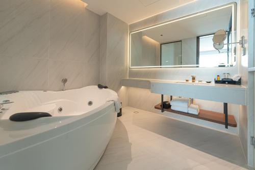a white bathroom with a tub and a sink at Champasak Grand Hotel in Pakse