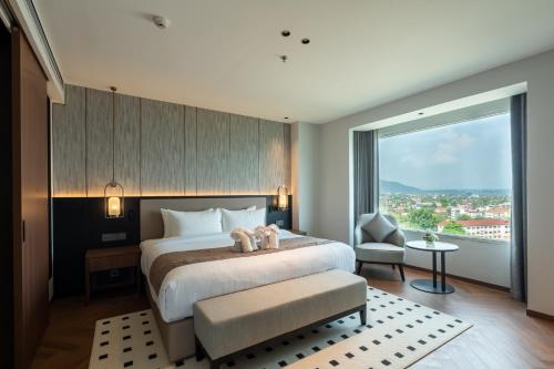 a bedroom with a large bed and a large window at Champasak Grand Hotel in Pakse