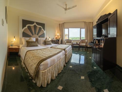 a hotel room with a large bed and a television at Hotel Clarks Shiraz in Agra
