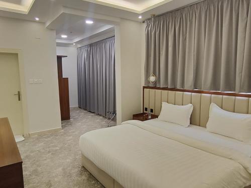 a bedroom with a large white bed and a window at أصالة الشروق حائل in Hail