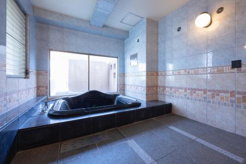 a large bathroom with a bath tub with a window at ホテルリノ in Kitakyushu