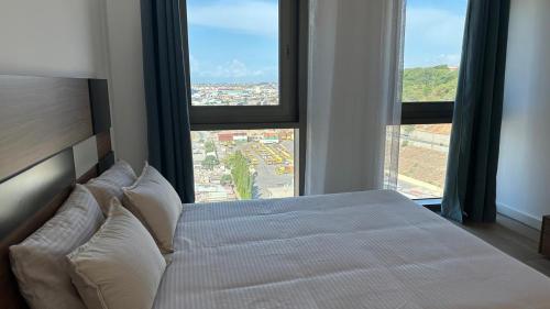 a bedroom with a white bed with large windows at Edifício Kings Tower T2-02 in Luanda