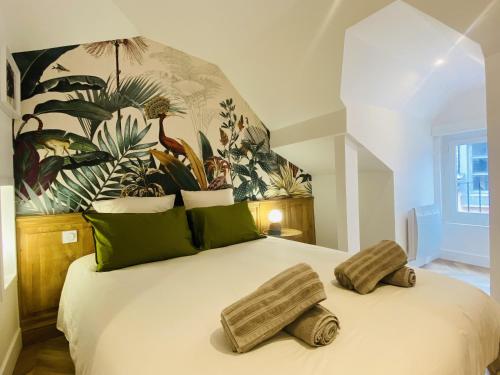 a bedroom with a large white bed with green pillows at La PARENTHESE RUTHENOISE in Rodez