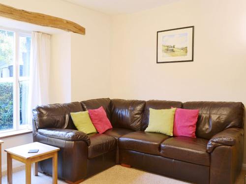 a brown leather couch in a living room with colorful pillows at Beny Cot in Keswick