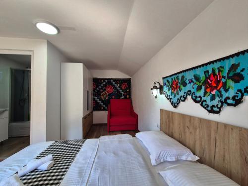 a bedroom with a bed and a red chair at Casa Papițu in Vadu Izei