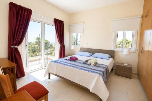 a bedroom with a bed and a large window at Unique Beach Luxurious Villas in Ayia Napa