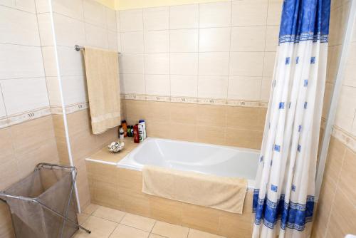 a bath tub in a bathroom with a blue shower curtain at Unique Beach Luxurious Villas in Ayia Napa