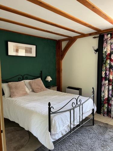 a bedroom with a bed with a green wall at Chez Jallot - Lower Gite in Vidaillat