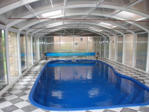 a large swimming pool with blue water in a room at Shallcross Hall Cottage - Toddbrook - Whaley Bridge in Taxal