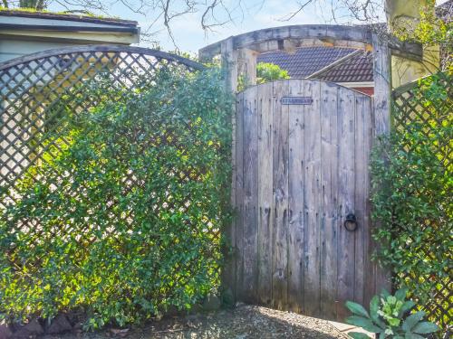 an old wooden gate in a fence with a hedge at Starboard Cottage in Winterton-on-Sea