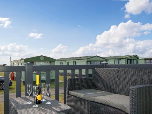 a table with a bottle of wine and glasses on a balcony at Premier Caravan 10 in Tywyn