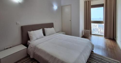 a white bedroom with a large bed and a window at Edifício Kings Tower T2-06 in Luanda