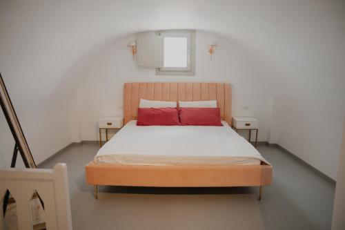 a bedroom with a bed with red pillows on it at The Lighthouse Sunset View Suites in Akrotiri