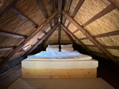 a bed in a thatch roofed room at Cabin by the pond in Wądołki Bućki