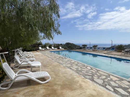 a row of lounge chairs next to a swimming pool at Holiday Home Le Terrazze del Geco Bungalow A - SLR300 by Interhome in San Lorenzo al Mare