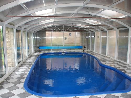 a large swimming pool with blue water in a room at Shallcross Hall Cottages - Combs in Taxal