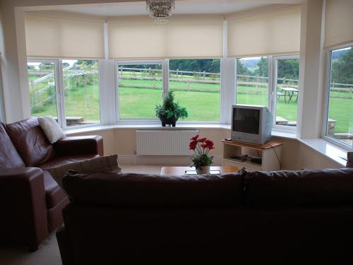 a living room with a couch and a tv at Shallcross Hall Cottages - Blackbrook in Taxal