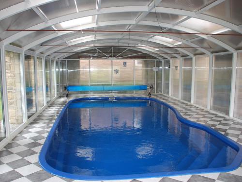 a large swimming pool in a room with a tiled floor at Shallcross Hall Cottages - Blackbrook in Taxal