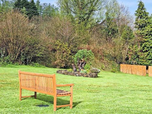 a wooden bench sitting in the grass in a yard at Dôl Werdd Lodge in Glanamman
