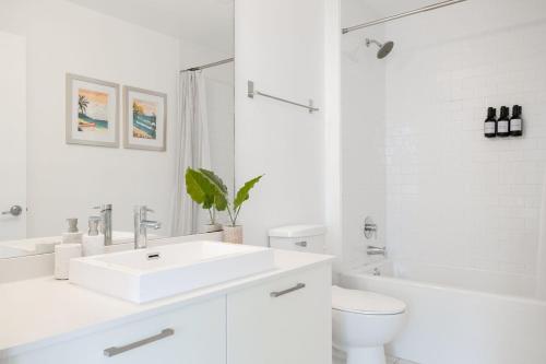 a white bathroom with a sink and a toilet at Stylish Pool Stay Near Brickell & Beach in Miami