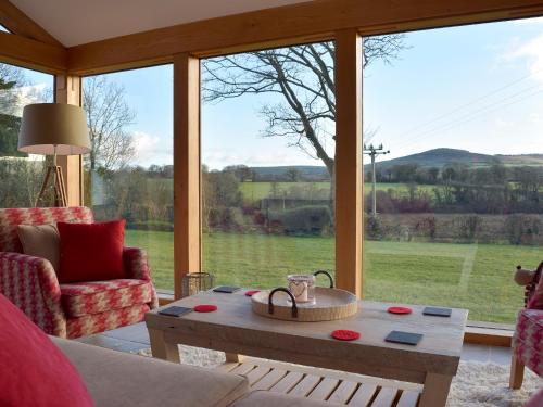 a living room with a table and a large window at Fountain Hill in Eglwyswrw