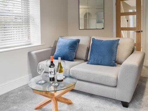 a living room with a couch and wine bottles on a table at Station Cottage in Silverdale