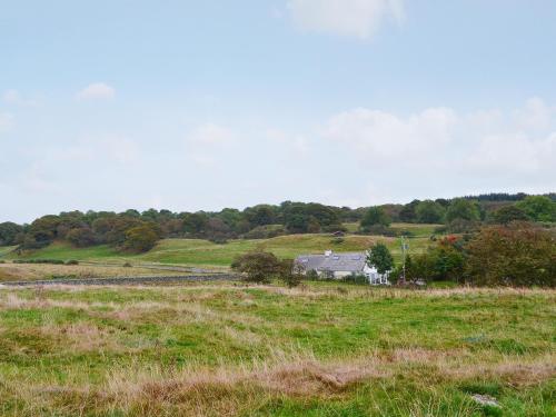 a field of grass with a house in the background at Horsepark Cottage in Girthon