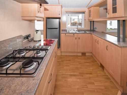 a kitchen with wooden cabinets and a stove top oven at Stanley's Sanctuary in Boot