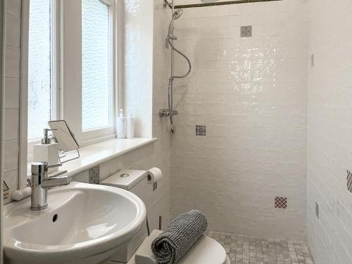a white bathroom with a sink and a toilet at Olveston in Llandudno