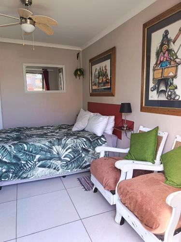 a bedroom with two beds and two chairs at Studio On Fairway in Langebaan