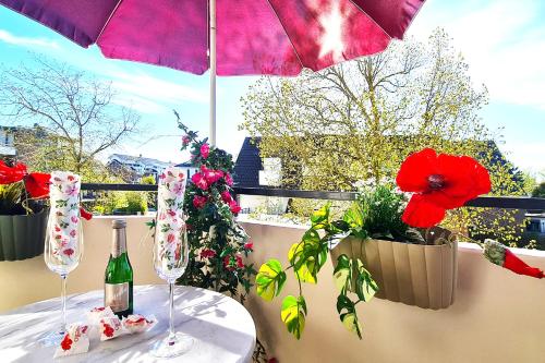 a table with two wine glasses and flowers on a balcony at Strandliebe in Scharbeutz, 150m zum Strand! Sonnenbalkon, ruhig gelegen, kostenfreier Parkplatz, Fahrstuhl in Scharbeutz