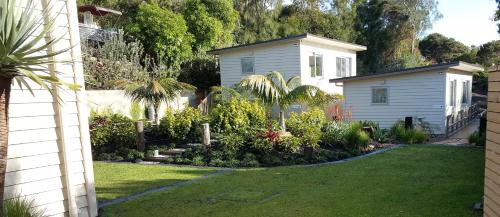 a garden with a white house and some plants at Oneroa Secret Garden Apartments in Oneroa