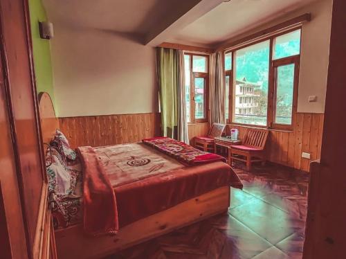 a bedroom with a bed and a table and windows at Negi Wooden House in Manāli
