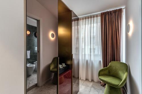 a bathroom with a green chair and a mirror at Barberini 16- Boutique Hotel in Rome