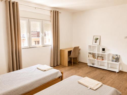 a room with two beds and a desk and a table at Vila Elena in Gevgelija