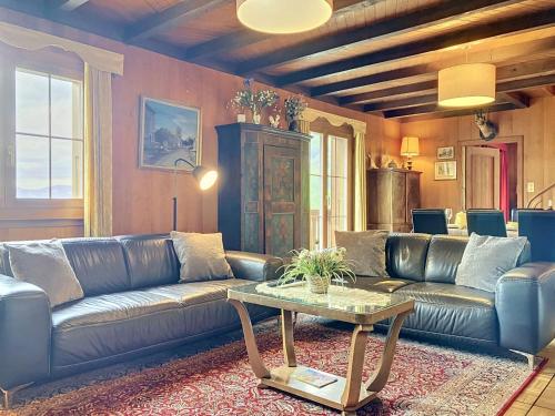 a living room with a leather couch and a table at Apartment Chalet Clairval by Interhome in Charmey