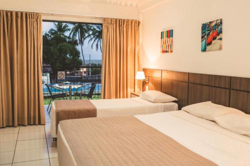 a hotel room with two beds and a balcony at Hotel SESI PB - Parque da Mata in Rio Tinto