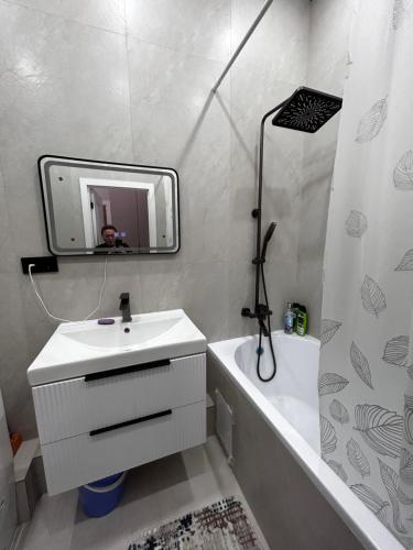 a bathroom with a sink and a tub and a mirror at River city-Сайран in Almaty