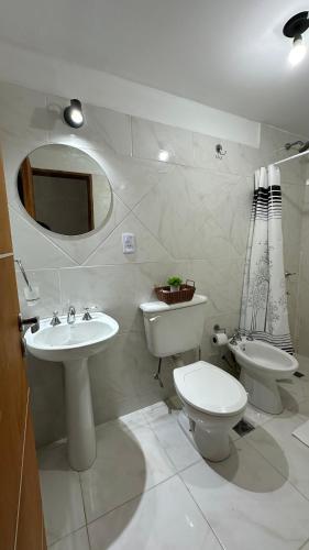 a bathroom with a sink and a toilet and a mirror at Norte Urban Suites in Resistencia