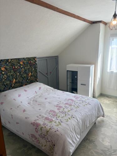 a bedroom with a large bed with a floral bedspread at Cozy apartment in Germainville